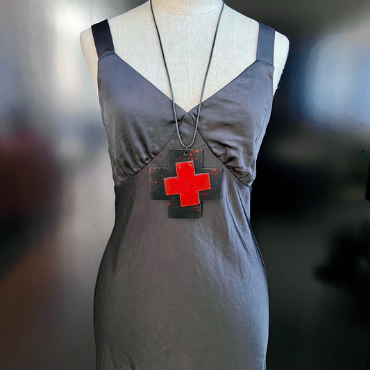 A mannequin wears a large black and red cross necklace