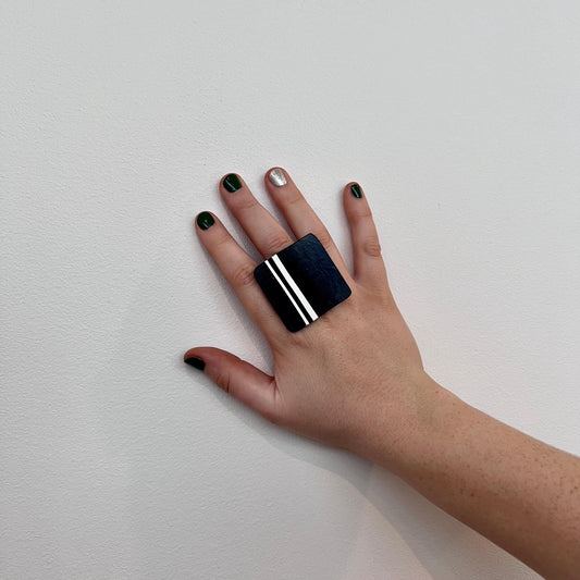 A woman's hand wearing a large repurposed rubber ring with a GT stripe