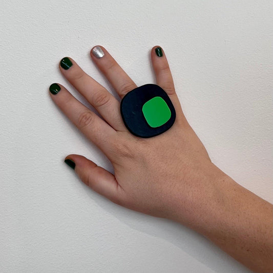 A woman's hand wearing a big black square ring made from reclaimed industrial rubber