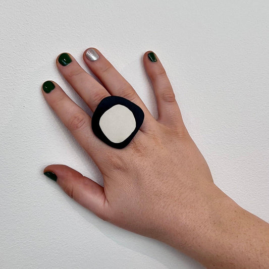 A woman's finger wears a  statement ring made of black and white repurposed rubber in an organic shape