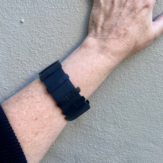 A woman's hand wearing A black Rubber Bangle topped with black rubber shards