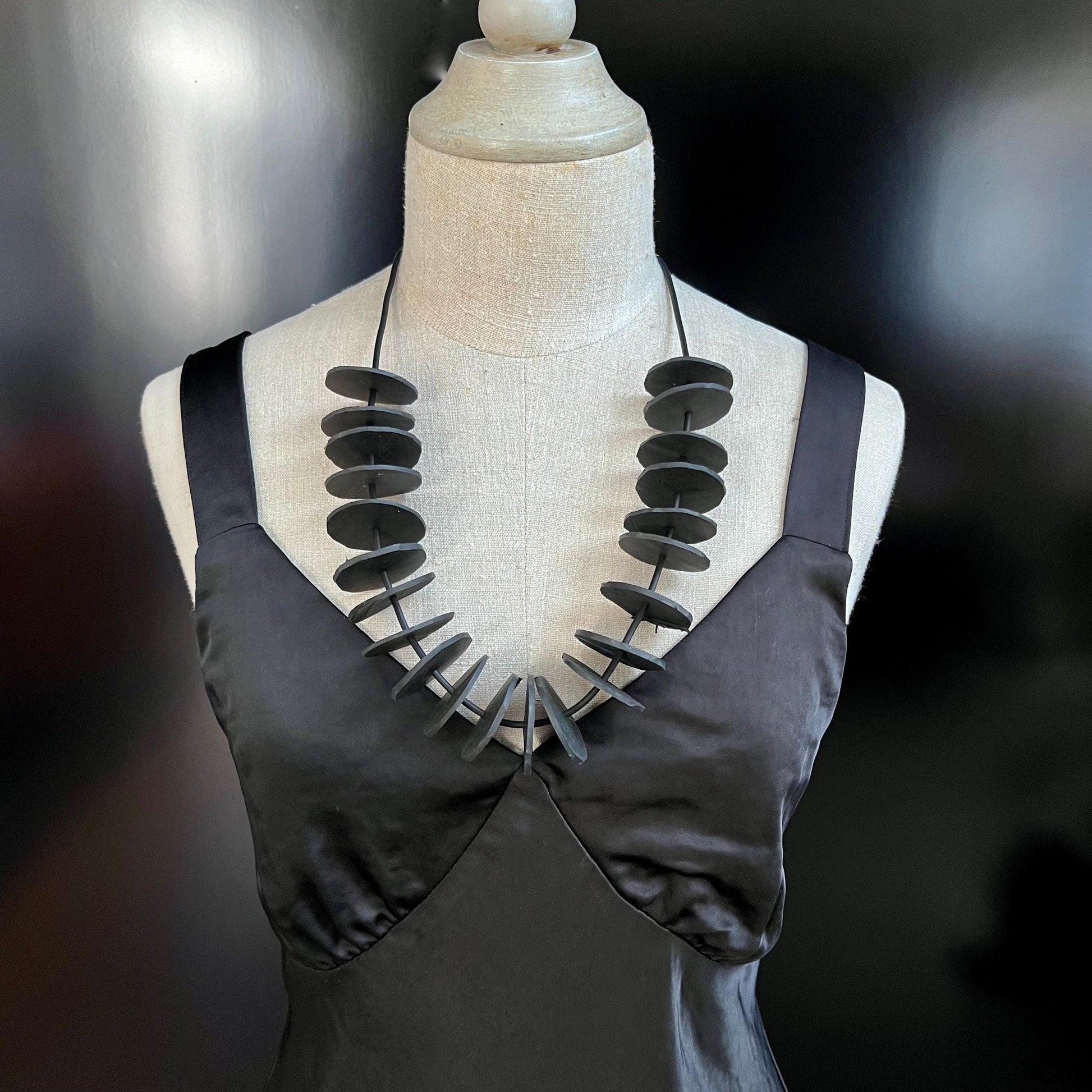 A mannequin wears a necklace with small circles on a strand at chest length