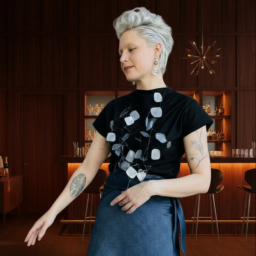 A woman wearing a silver necklace and black t-shirt in a mid century modern style bar
