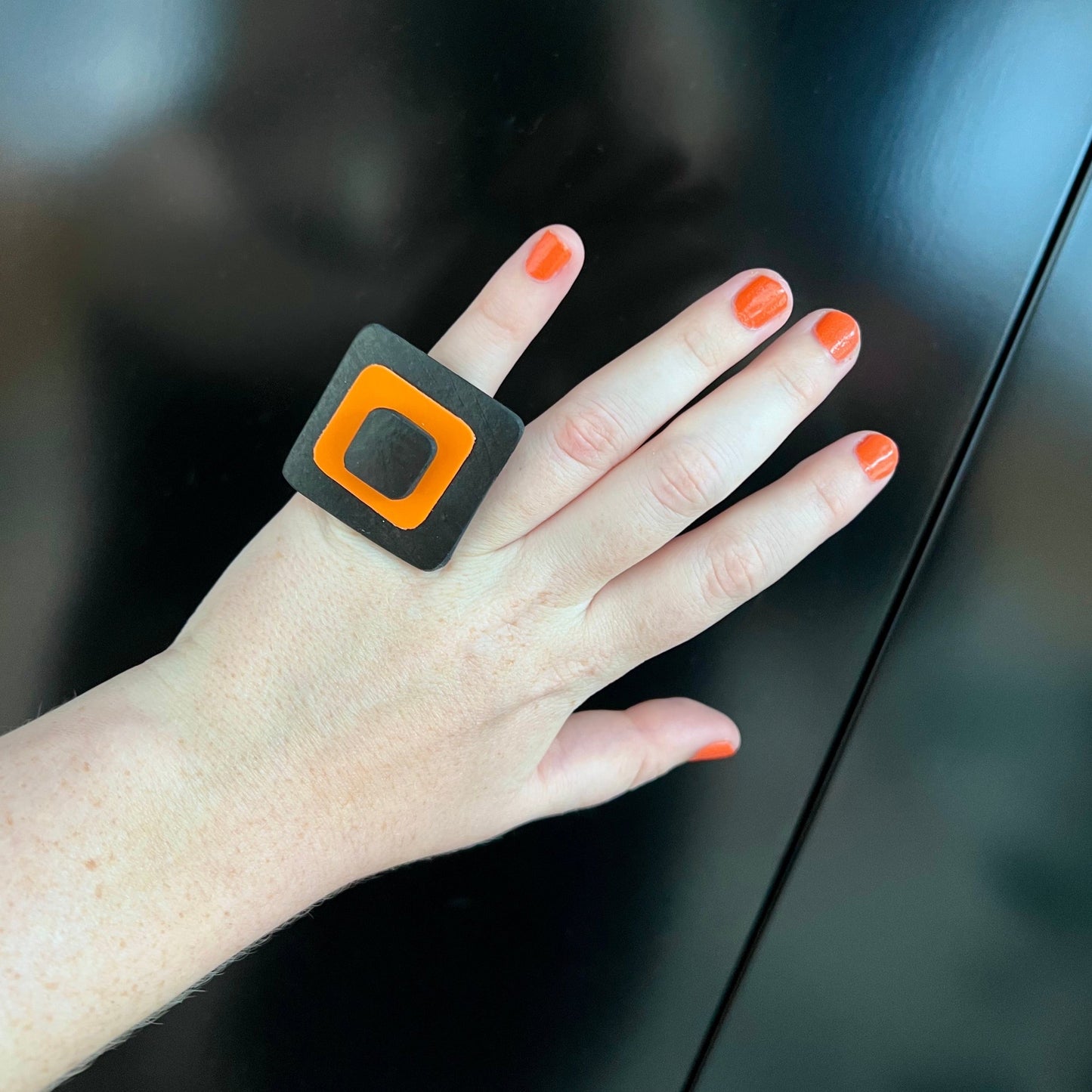 A woman's hand wearing an orange and black ring