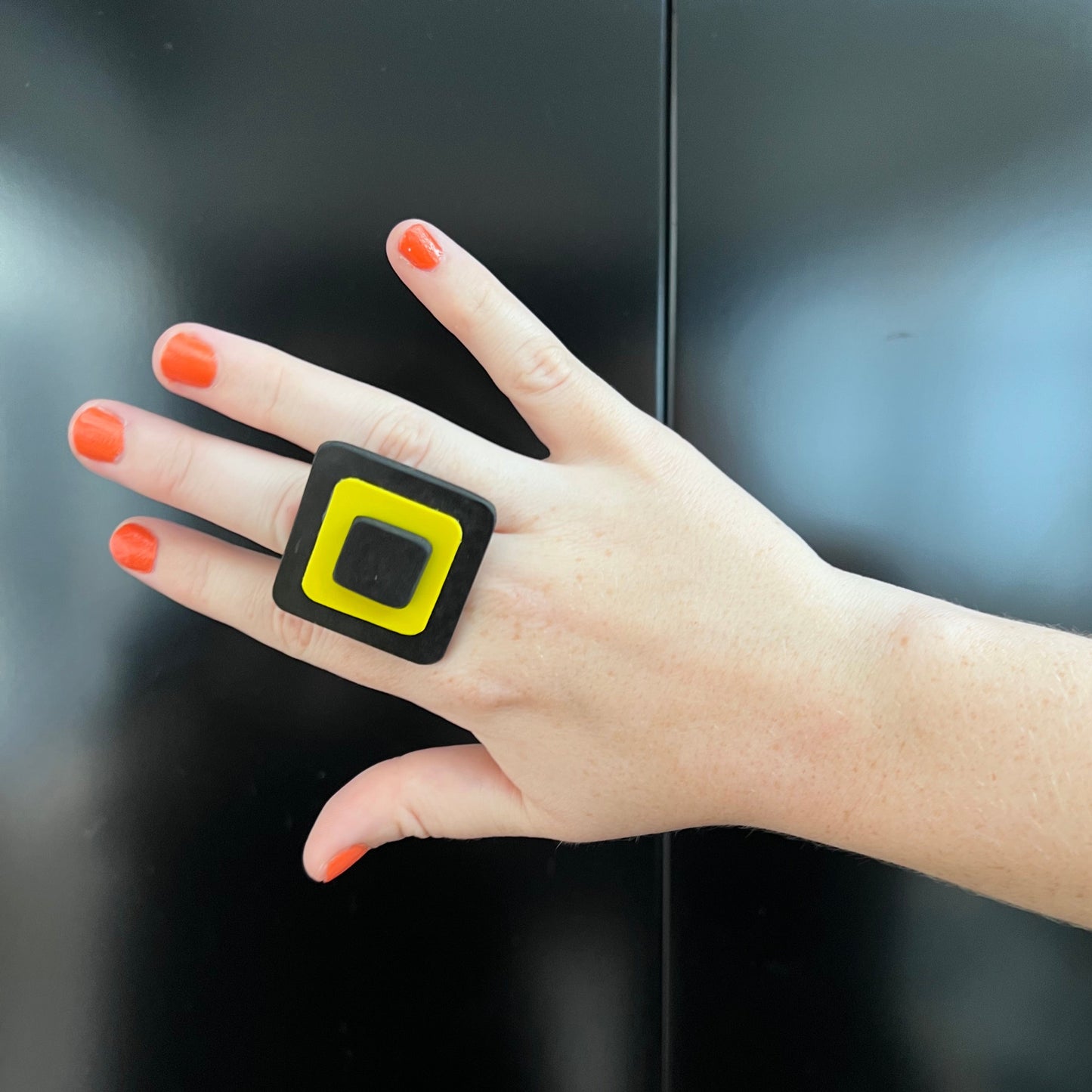 A woman's hand wearing a yellow and black ring