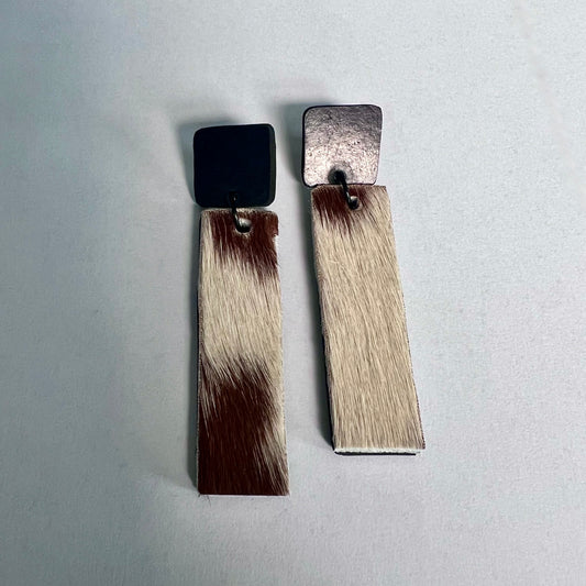 A pair of earrings of rubber and brown and white cowhide