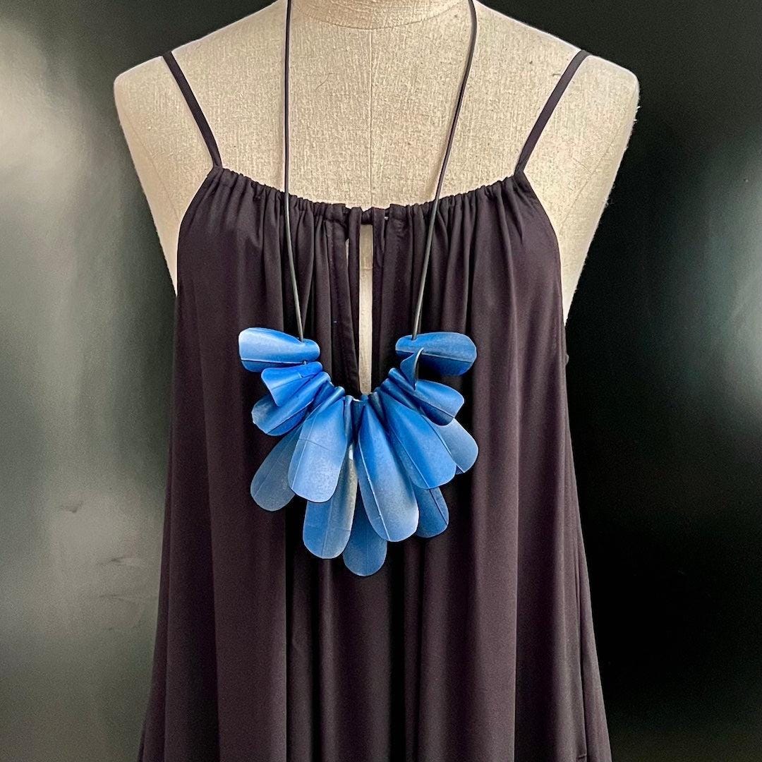 A mannequin wears a blue painted rubber necklace worn long