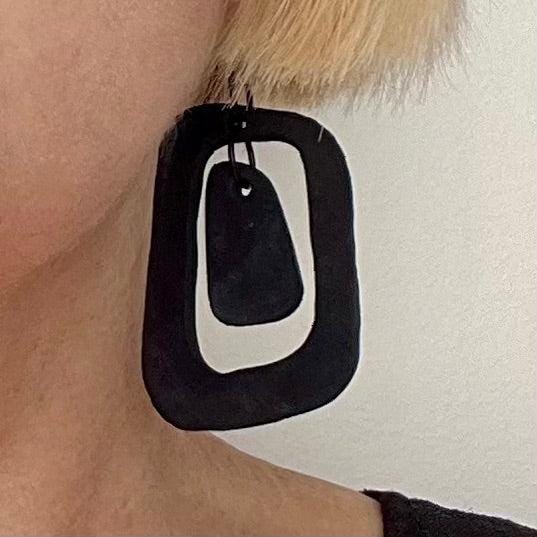 A woman wears a black dangle earring