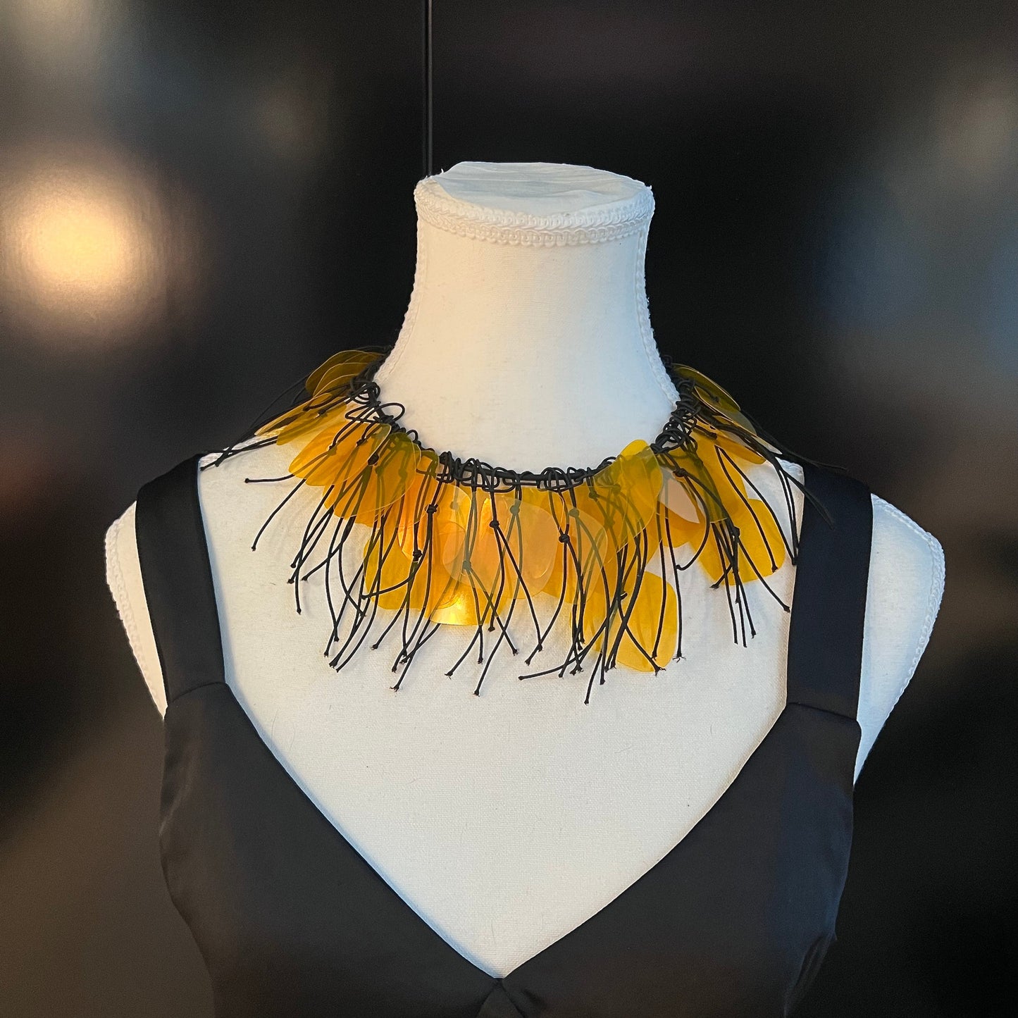 A mannequin wears a gold plastic necklace as a choker