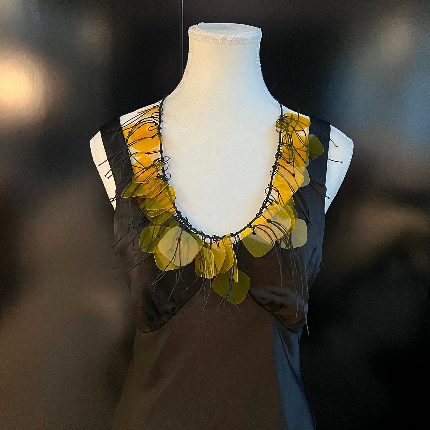 A mannequin wears a gold plastic necklace