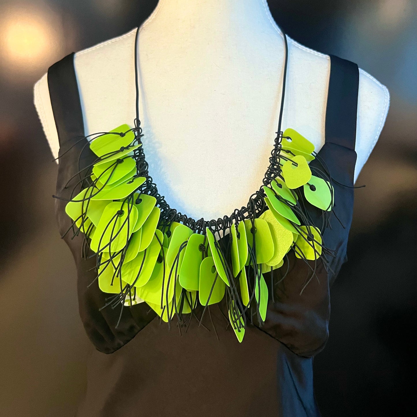 A mannequin wears a necklace made from green coloured recycled plastic