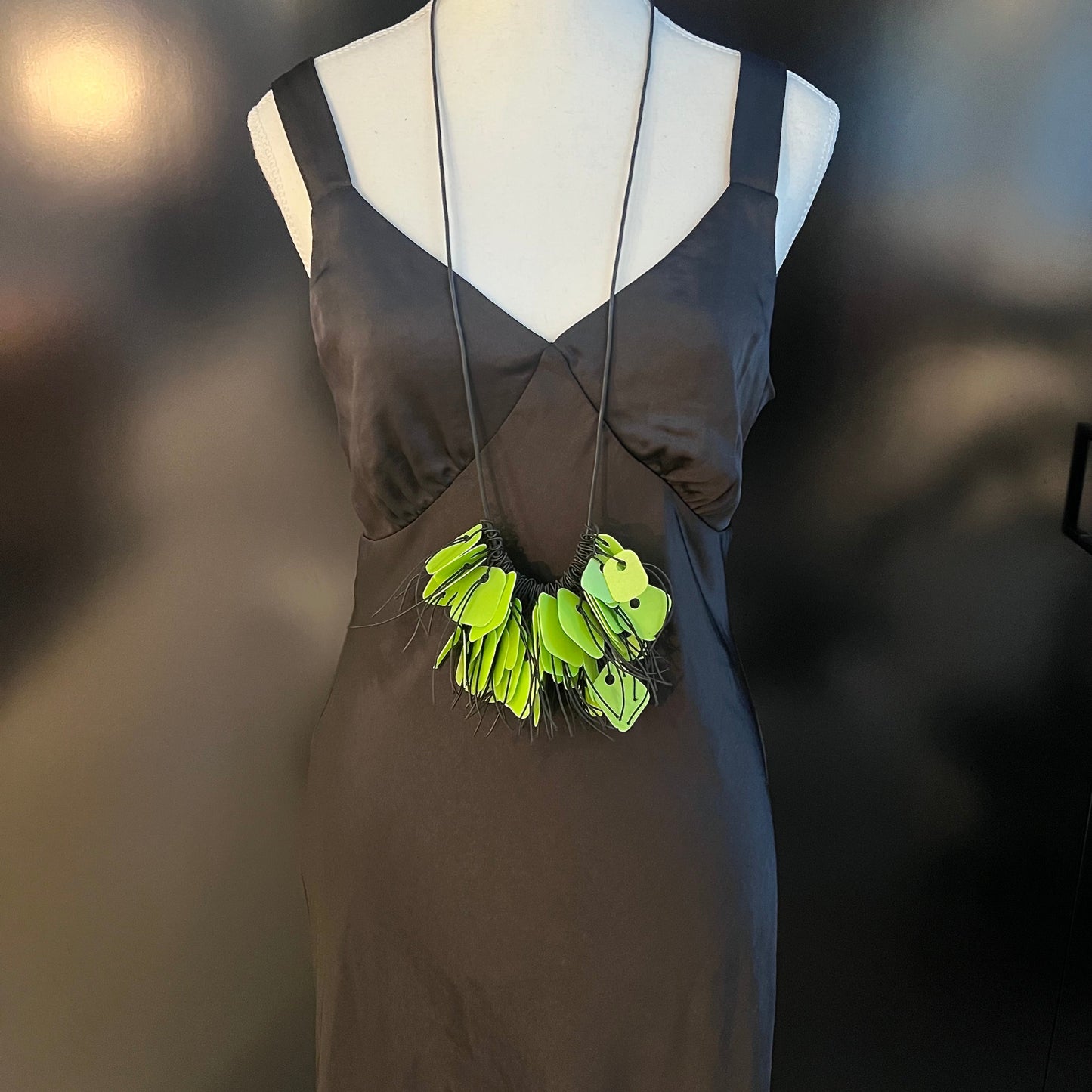 A mannequin wears a necklace made from green coloured recycled plastic