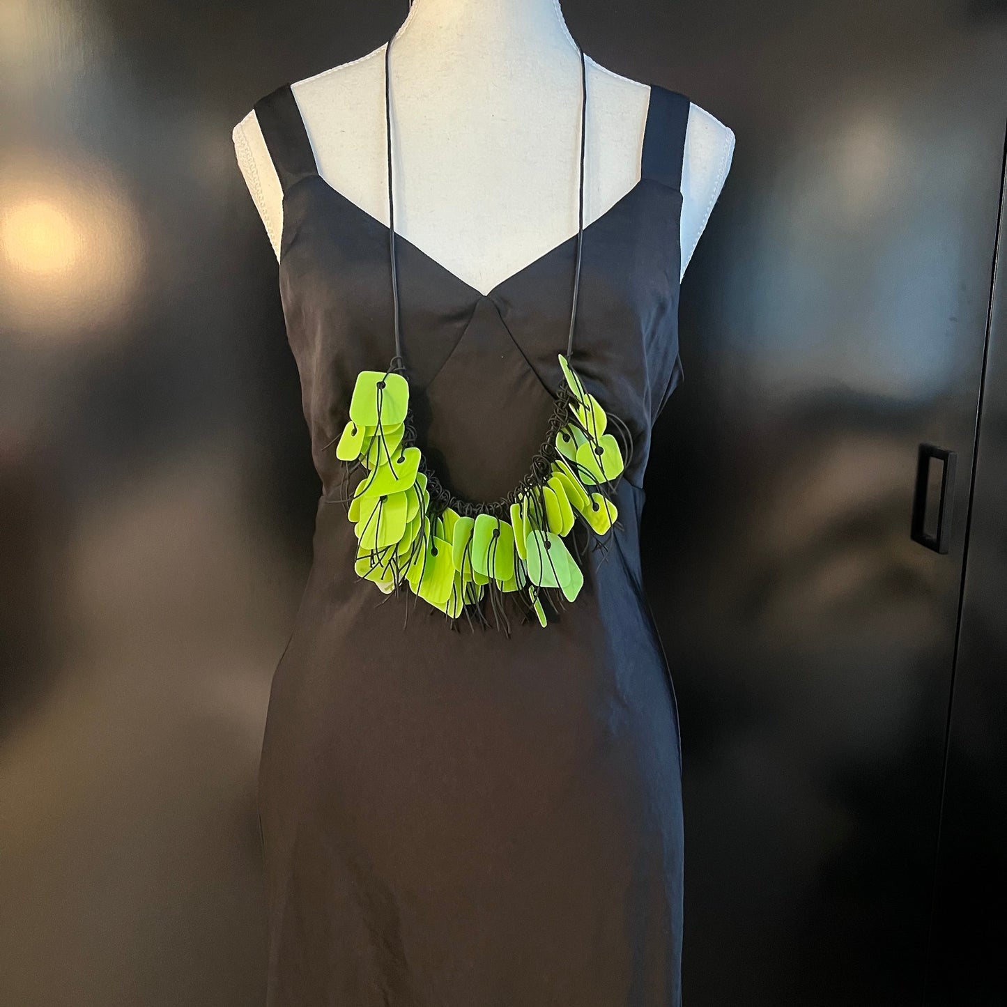 A mannequin wears a necklace made from green coloured recycled plastic