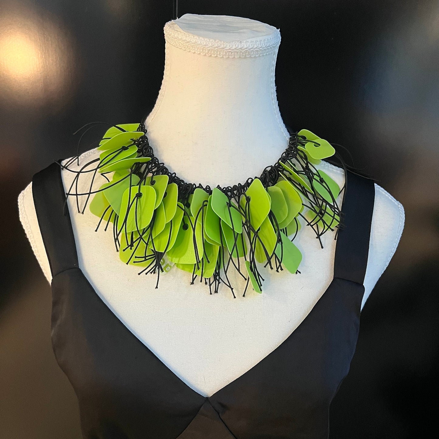 A mannequin wears a necklace made from green coloured recycled plastic as a choker
