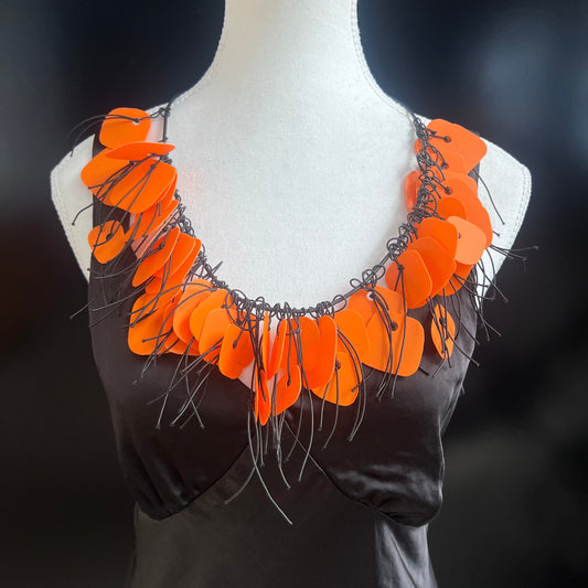 A mannequin wears an bright orange recycled plastic necklace