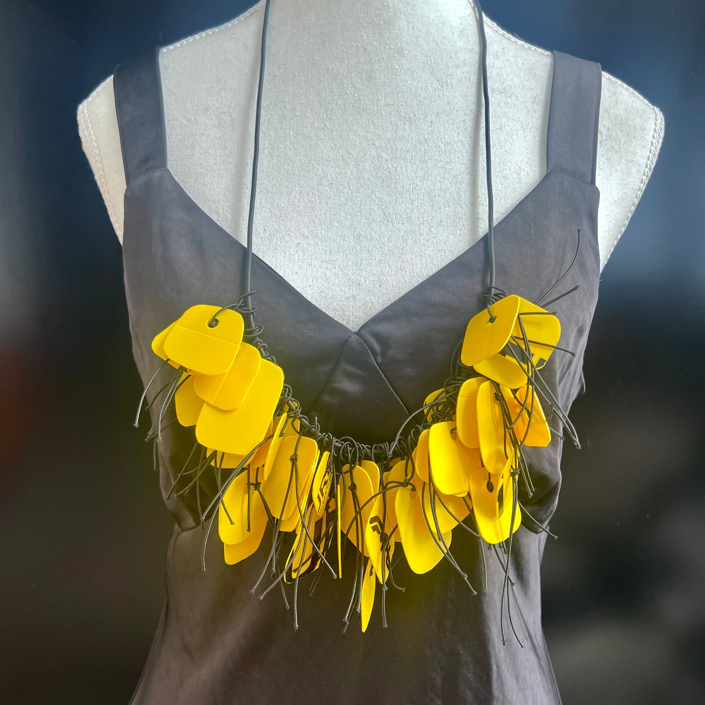 Yellow floral necklace on a mannequin with a dark background
