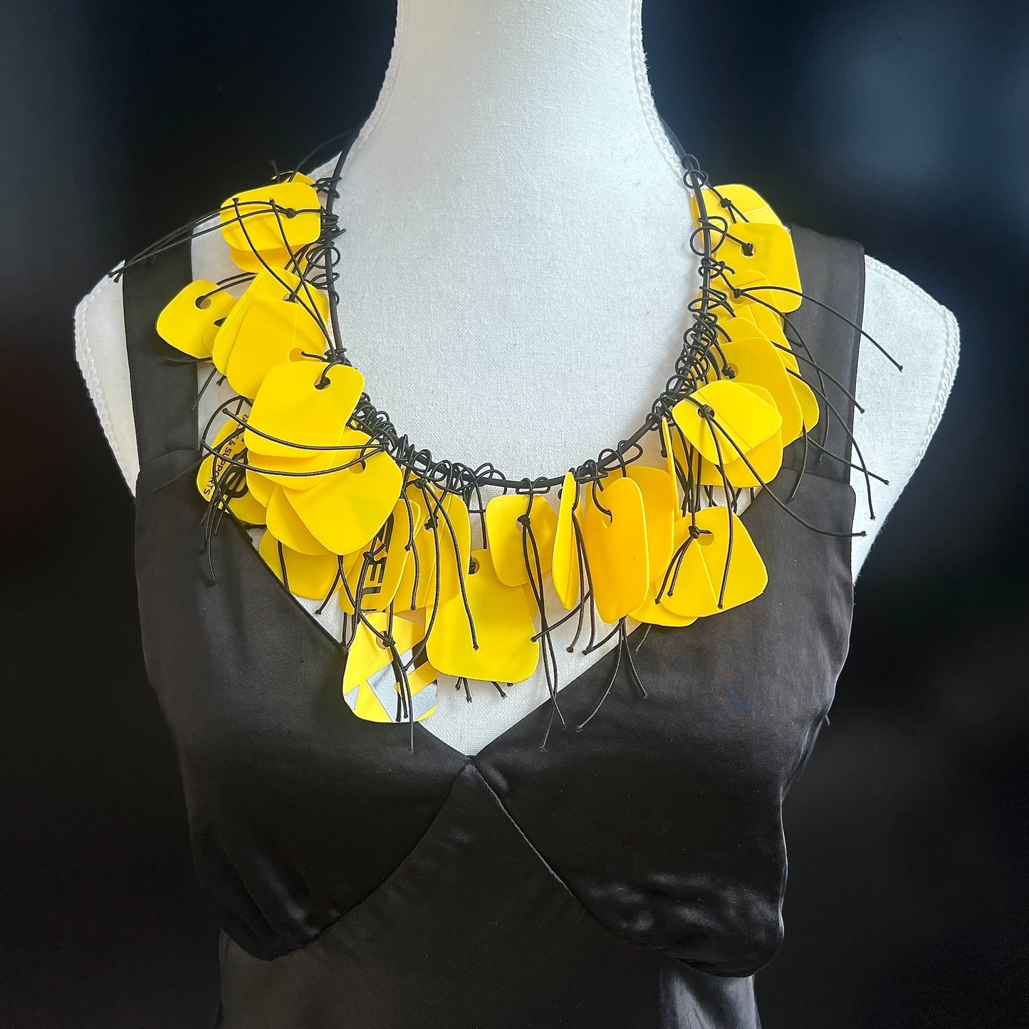 Yellow floral necklace on a mannequin against a dark background