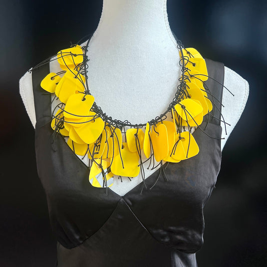 Yellow floral necklace on a mannequin against a dark background