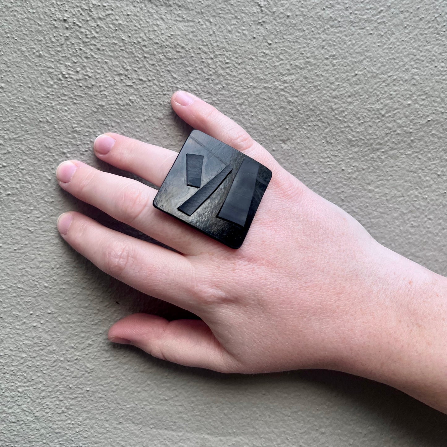 A woman's hand wearing a black square ring