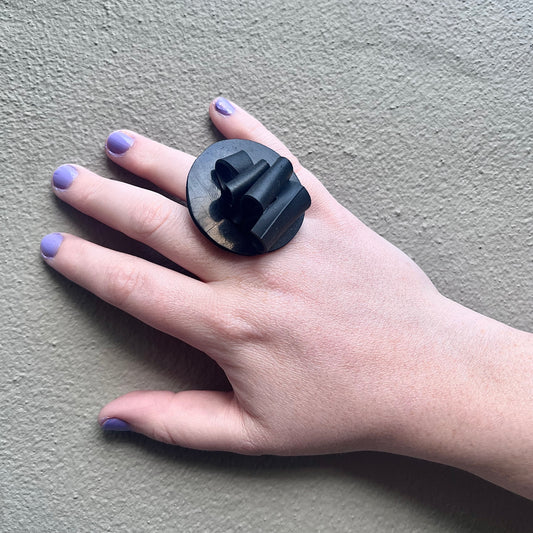 A hand wears a contemporary black ring made from rubber