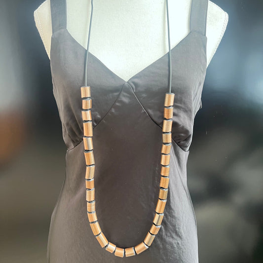 A mannequin wears a necklace of gold painted recycle rubber beads