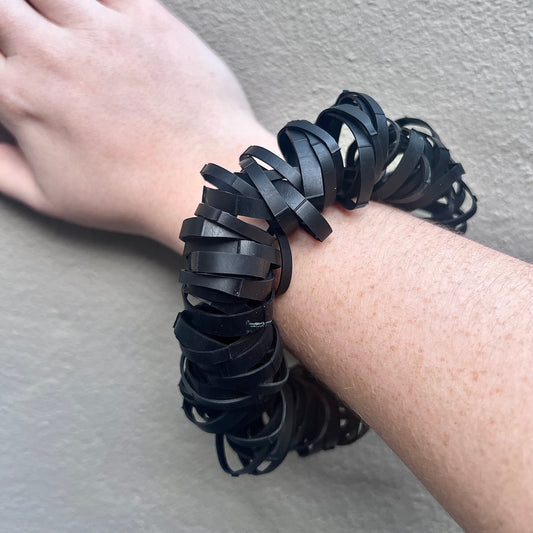 A hand wears a black bouncy rubber bracelet