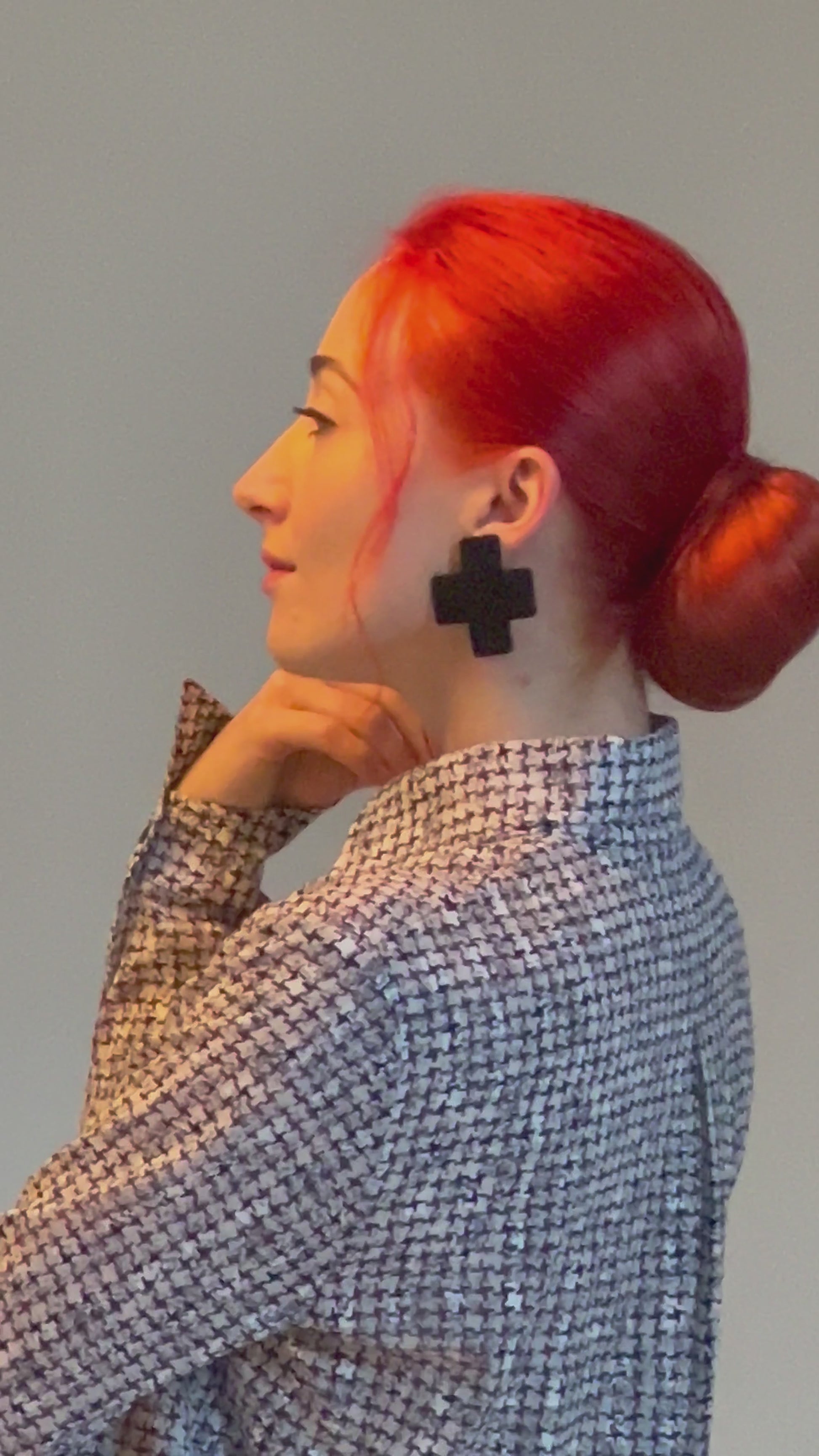 A model wears a pair of black cross stud earrings