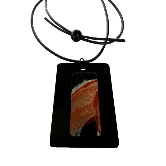 A rectangular black pendant with a strip of hand painted rubber overlay