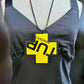 A mannequin wears a large pendant in the shape of a cross and layered with a black and yellow plastic cross with writing