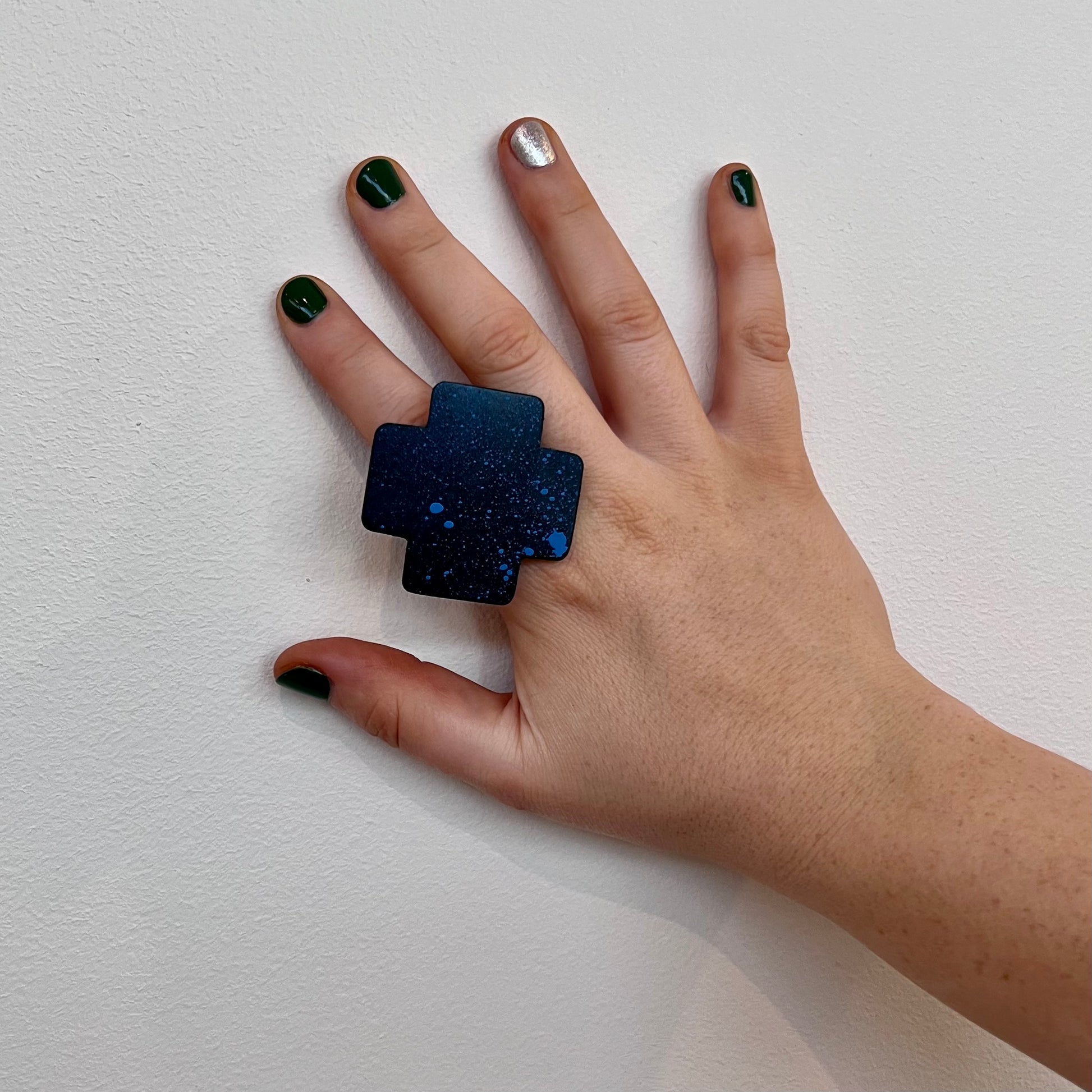 A woman's hand wears a large statement ring of repurposed rubber which has been spray painted