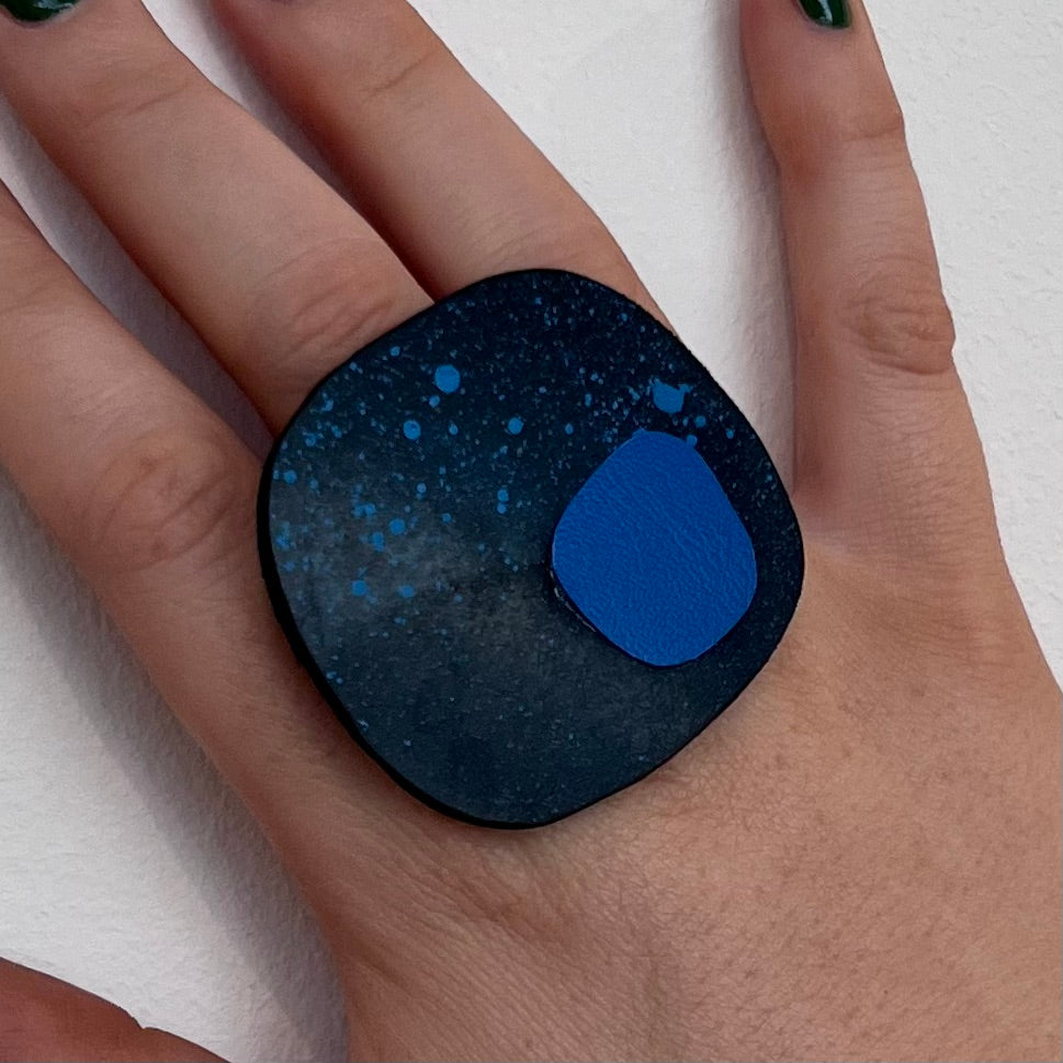 A woman's finger wearing a large painted rubber statement ring