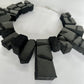 A large rectangular shaped choker of black rubber