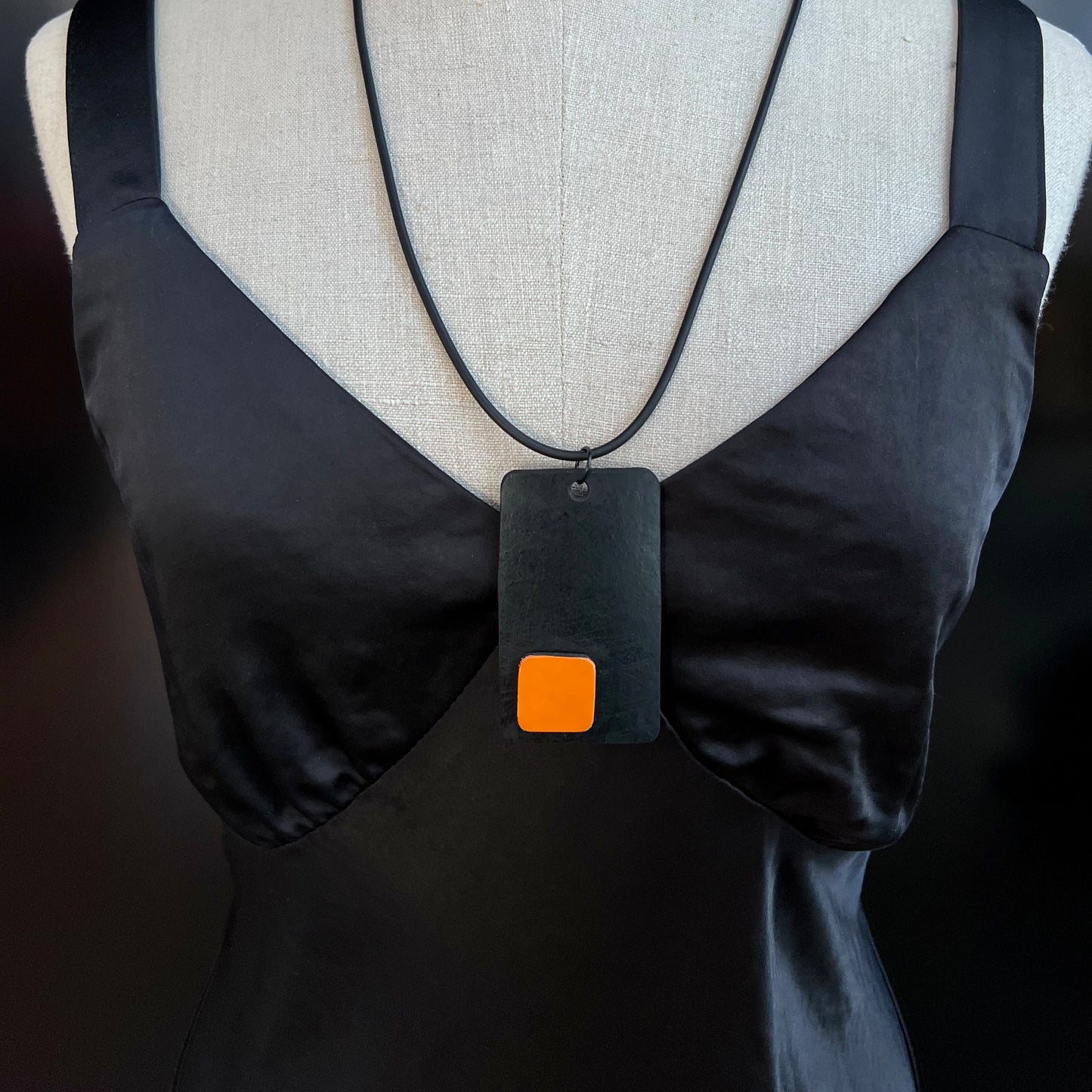 A mannequin wears and black and orange necklace