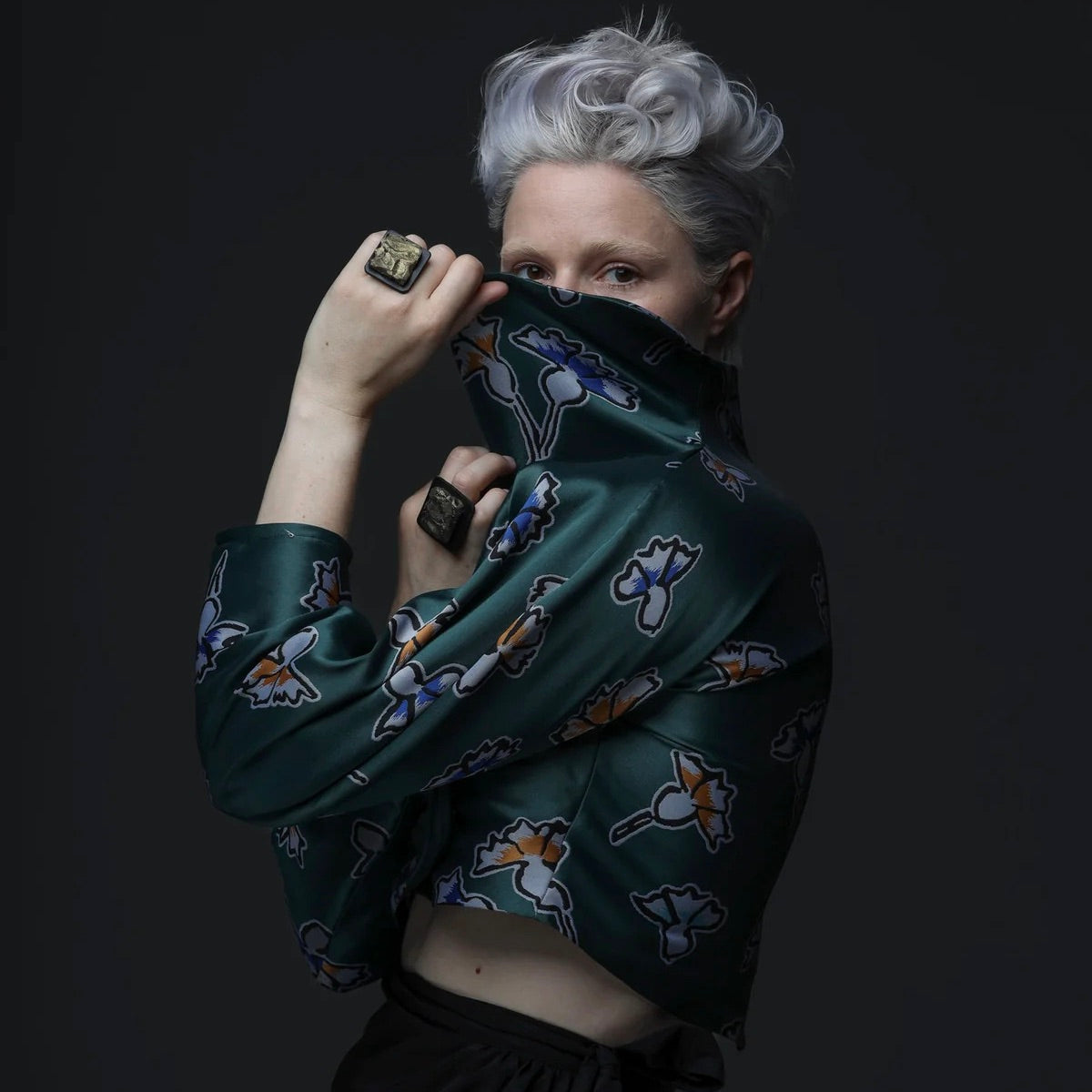 A model strikes a pose wearing two large square bronze chunky rings
