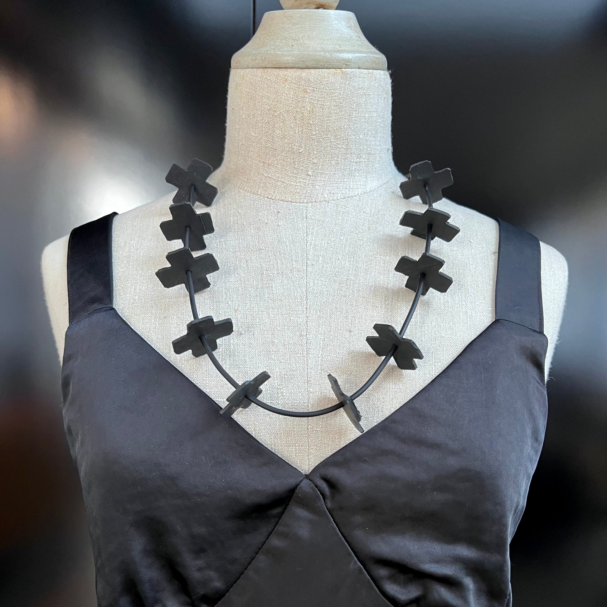 A mannequin wears a necklace of small rubber crosses