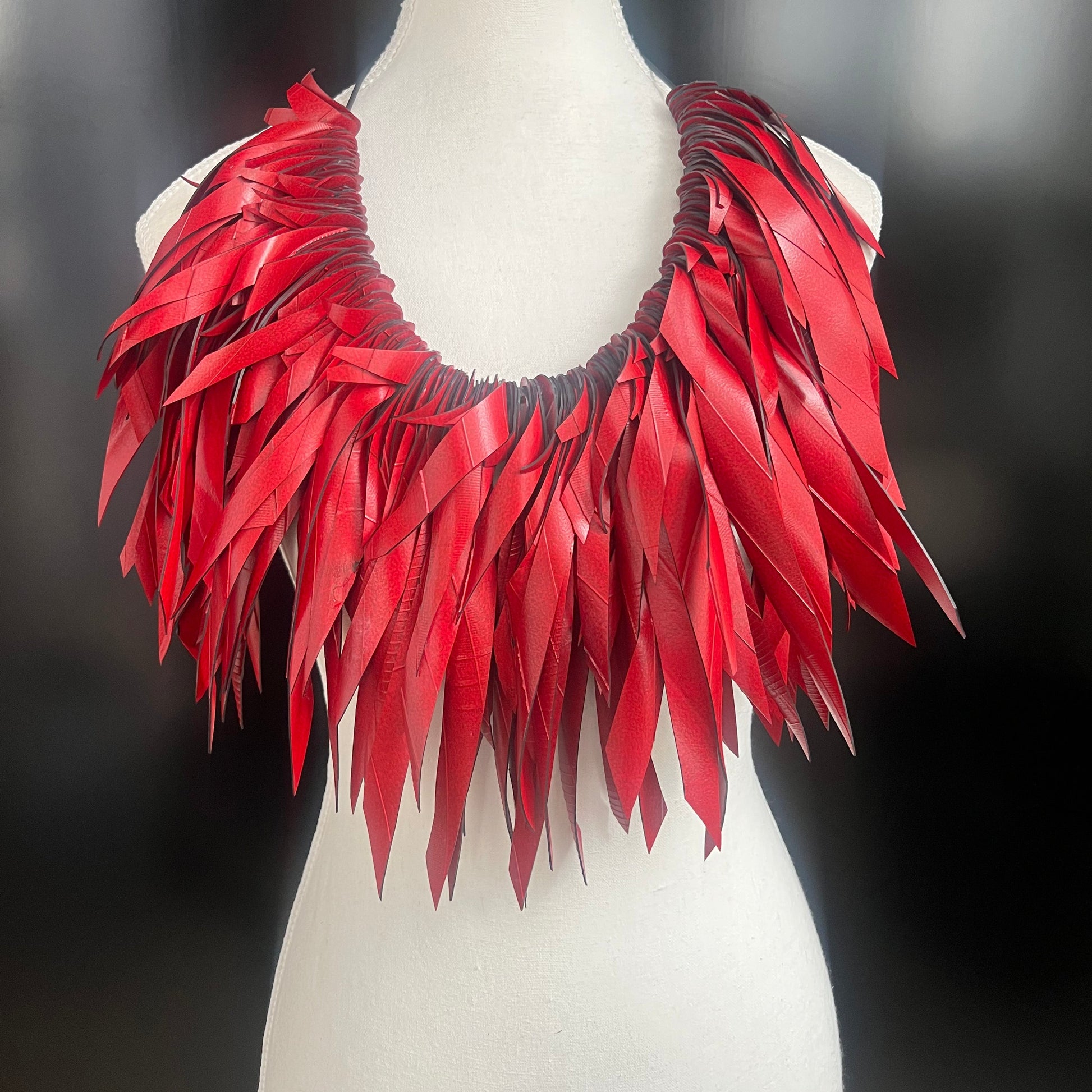 A mannequin displays a large red voluminous necklace