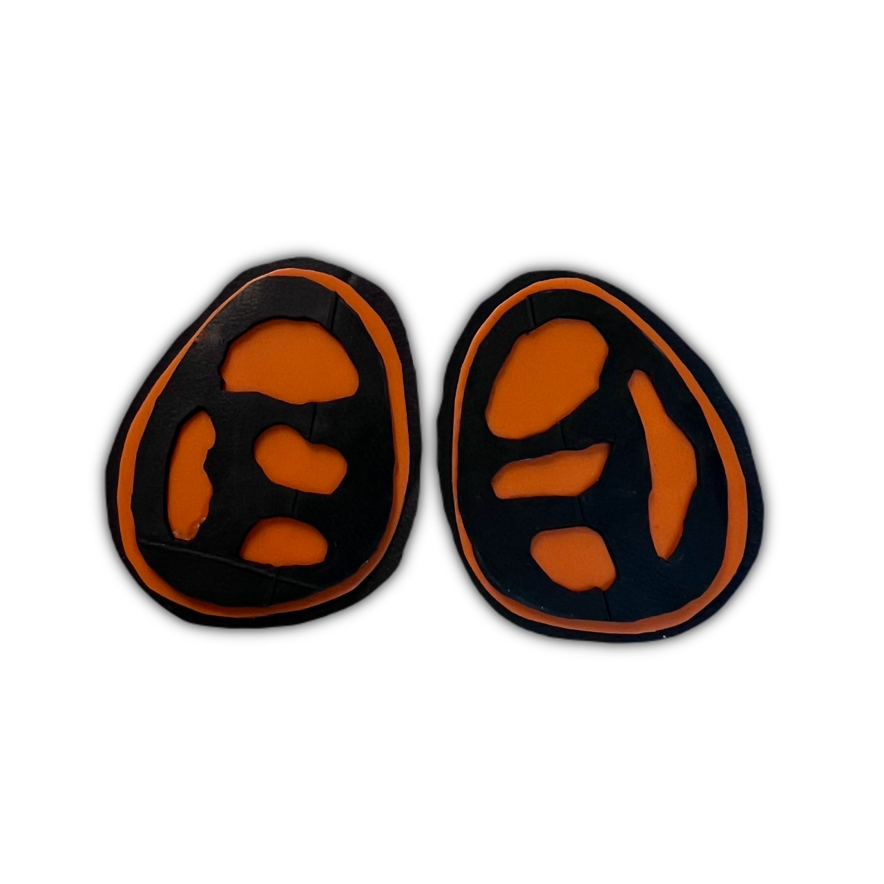 A pair of black and orange stud earrings with fossil like cut outs