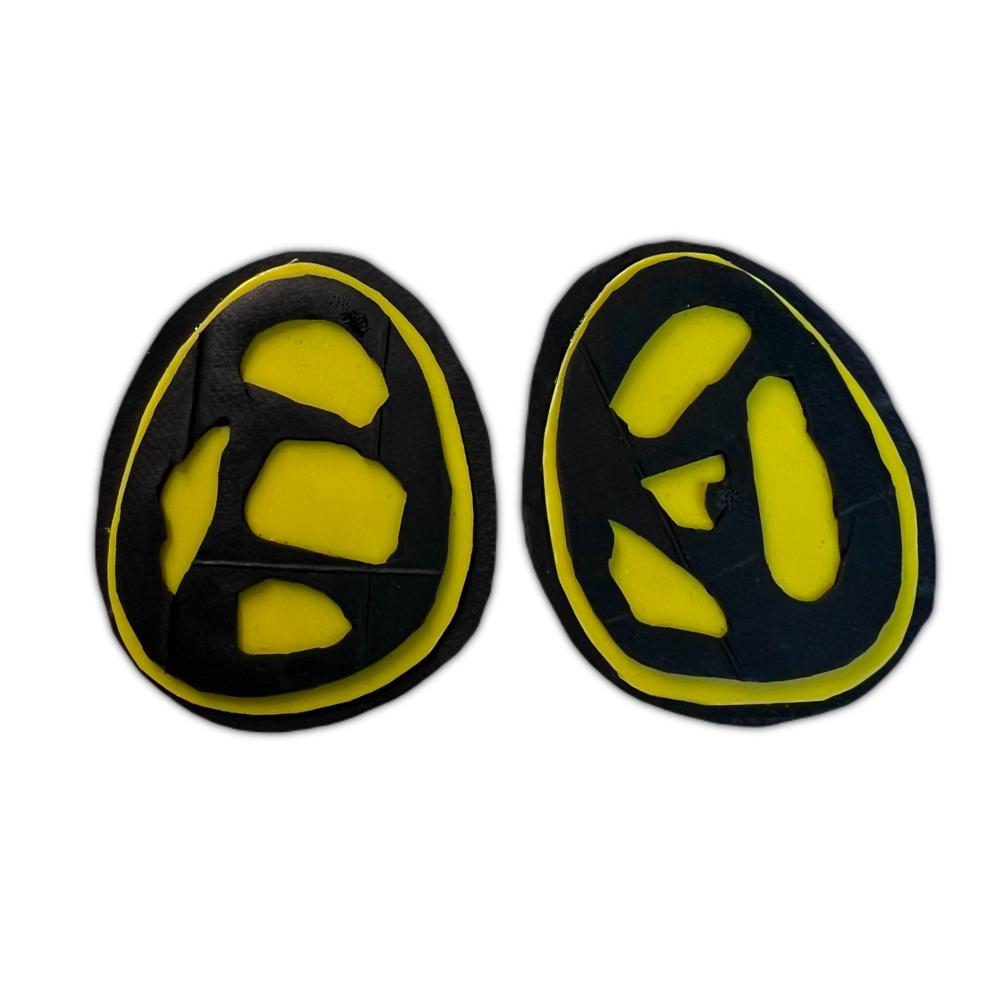 A pair of black and yellow stud earrings with fossil like cut outs