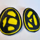 A pair of rubber and plastic yellow stud earrings with fossil like cut outs in close up