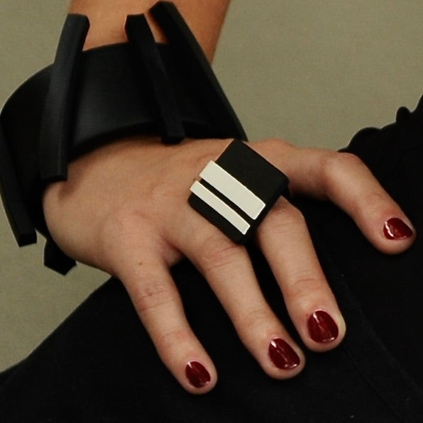 A woman wears a black rubber ring which features GT stripes