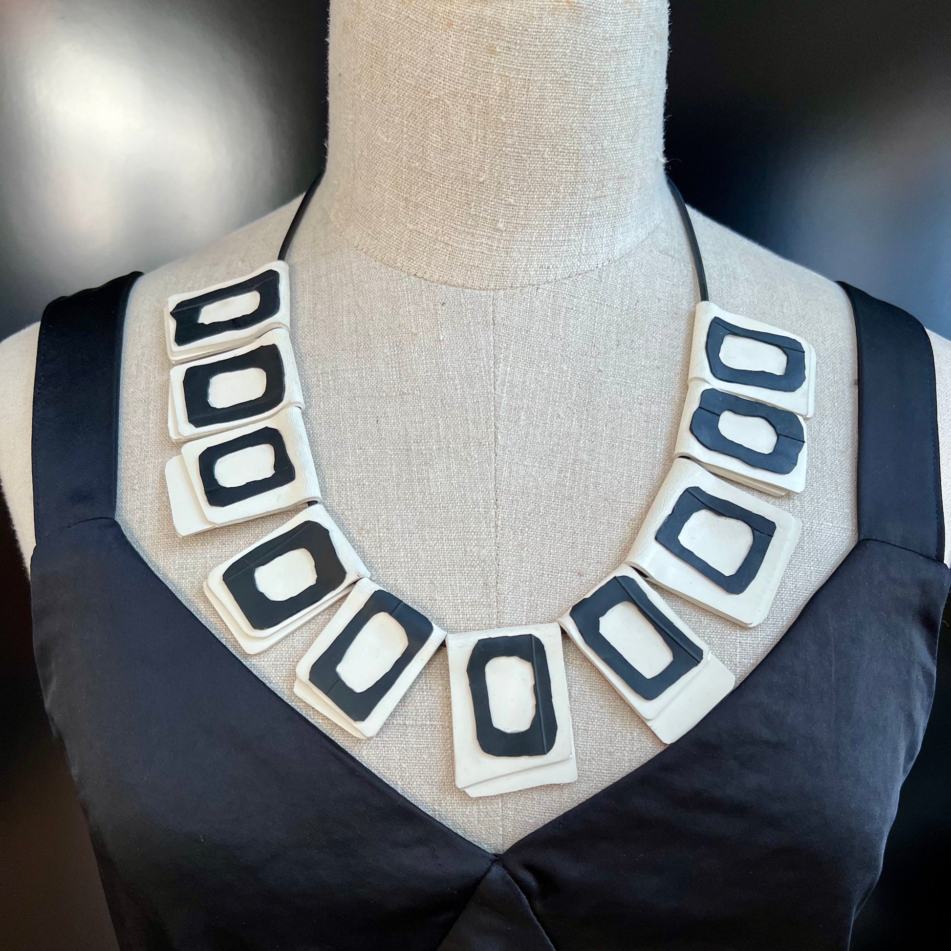 A mannequin wears a necklace of rubber geometric squares