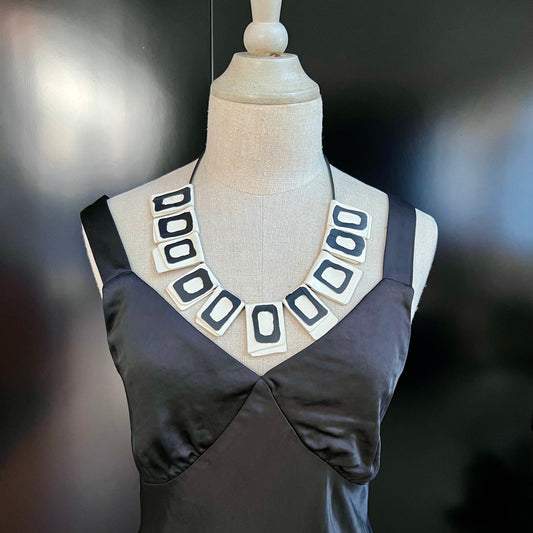 A mannequin wears a necklace of rubber geometric squares