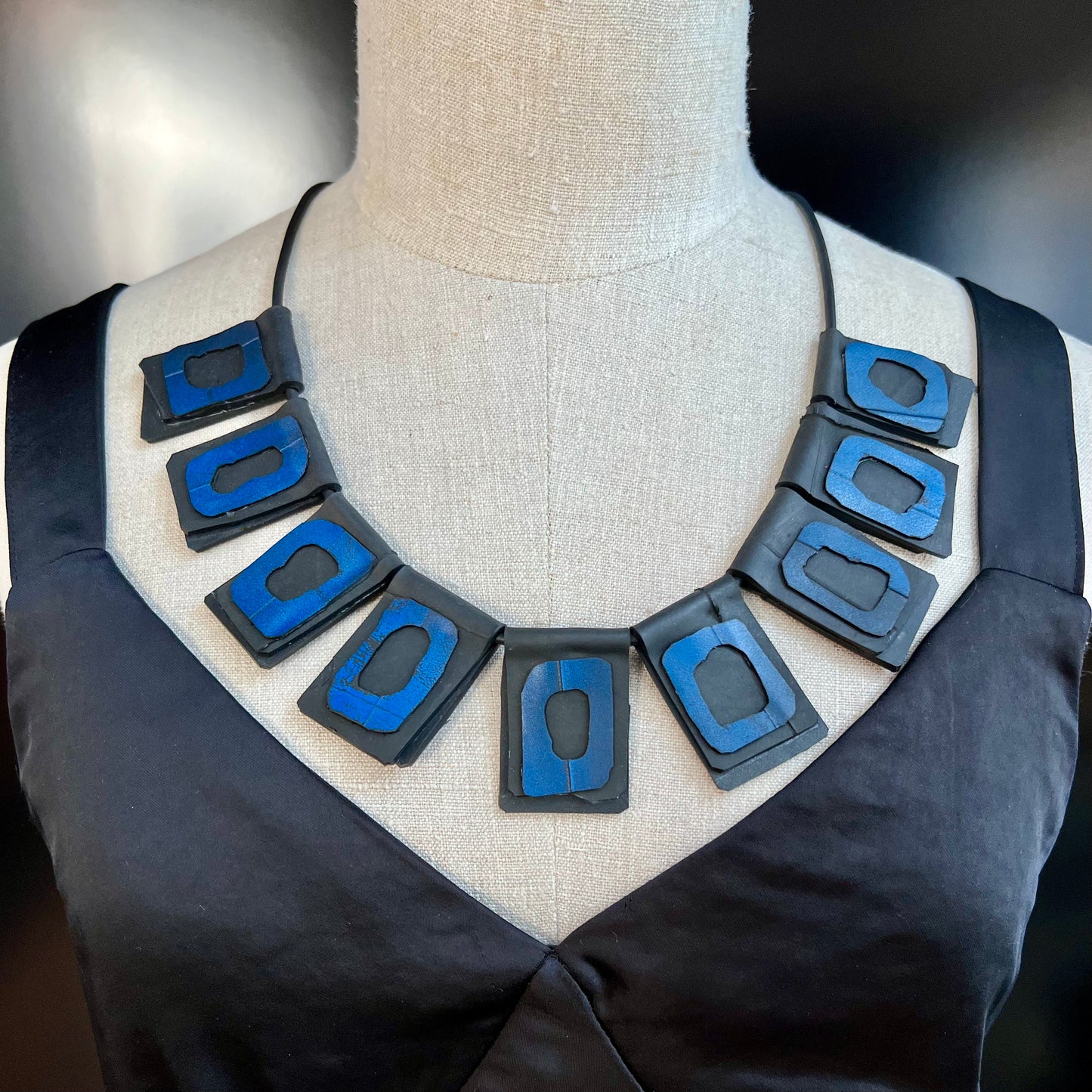 A mannequin wears a necklace of rubber geometric squares