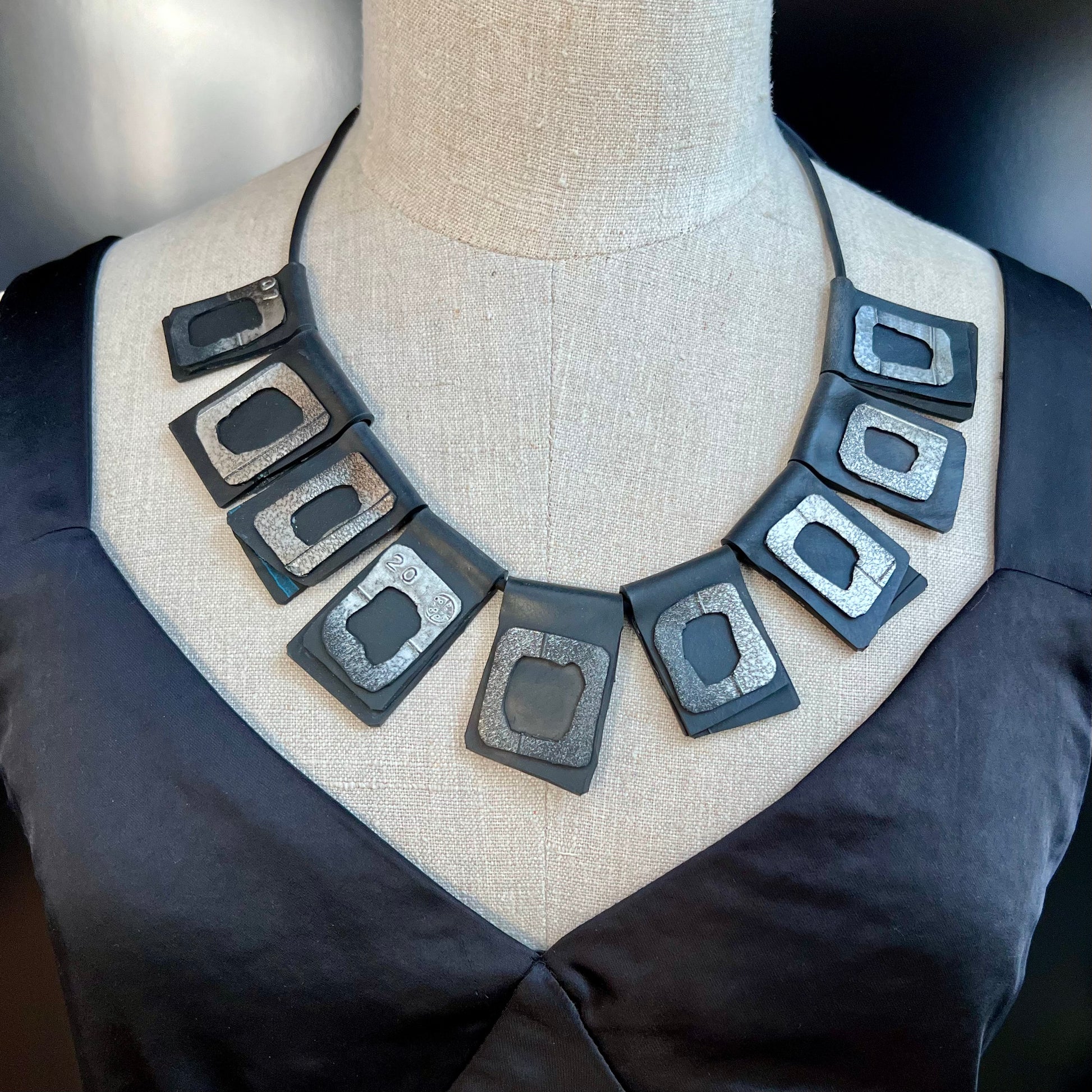 A mannequin wears a necklace of rubber geometric squares