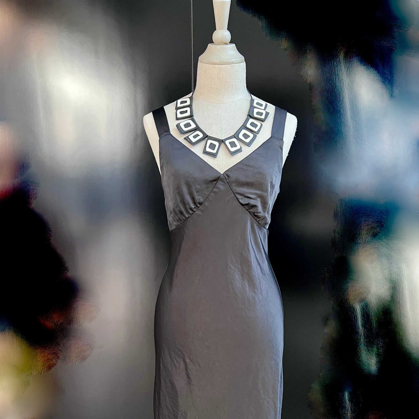 A mannequin wears a necklace of rubber geometric squares
