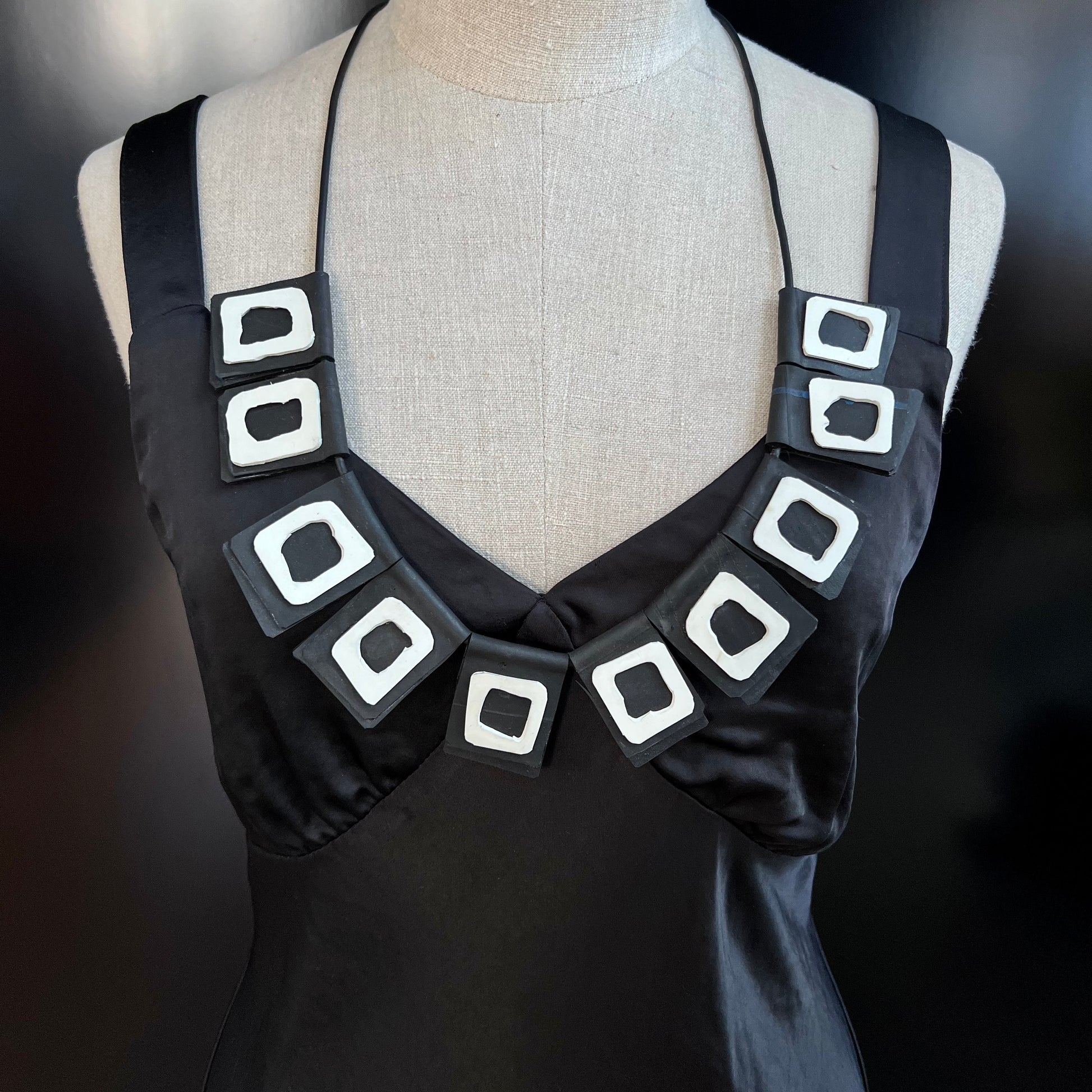 A mannequin wears a necklace of rubber geometric squares