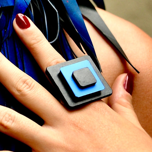 A woman wears a black rubber and blue plastic square ring