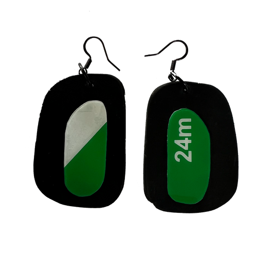 A pair of earrings with discs of rubber topped by discs of an ex exit sign plastic