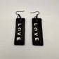 A pair of black and white earrings displaying the word LOVE