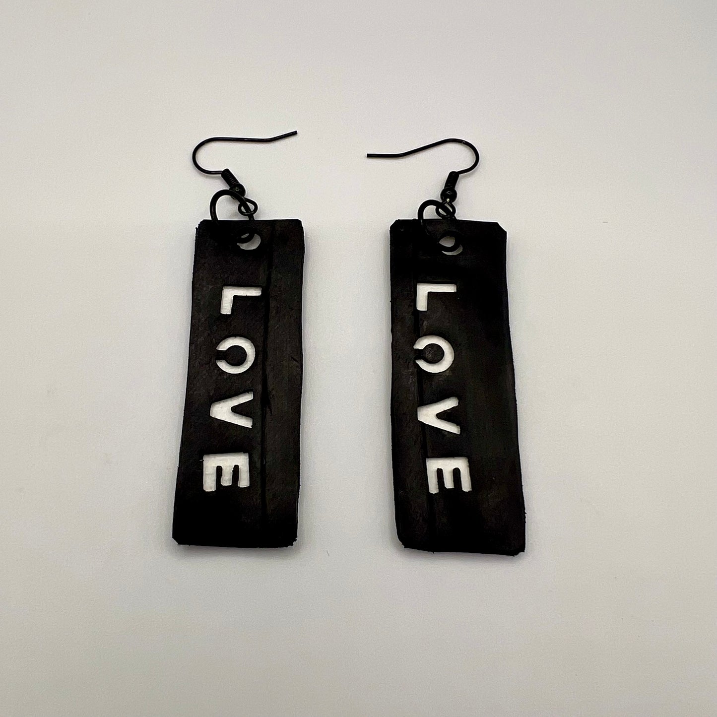 A pair of black and white earrings displaying the word LOVE